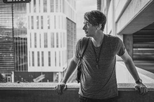 A Man in Crew Neck Shirt Leaning on Concrete Wall