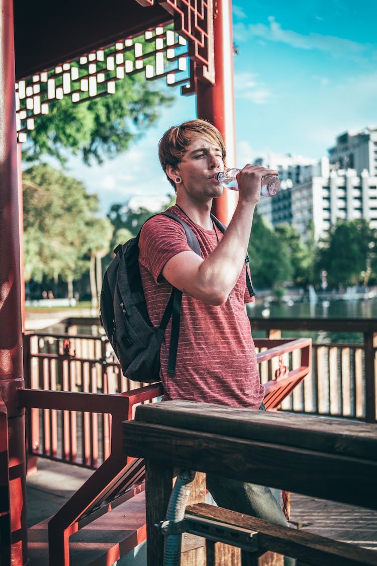 Man In A Striped Shirt Drinking A Bottled Water