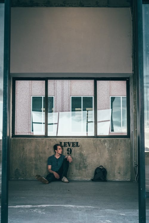 Man Sitting by the Wall in an Abandoned Building 