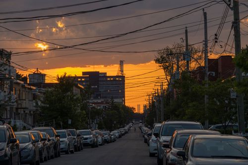 Free A picturesque sunset over a quiet street in Montréal, showcasing parked cars and colorful sky. Stock Photo
