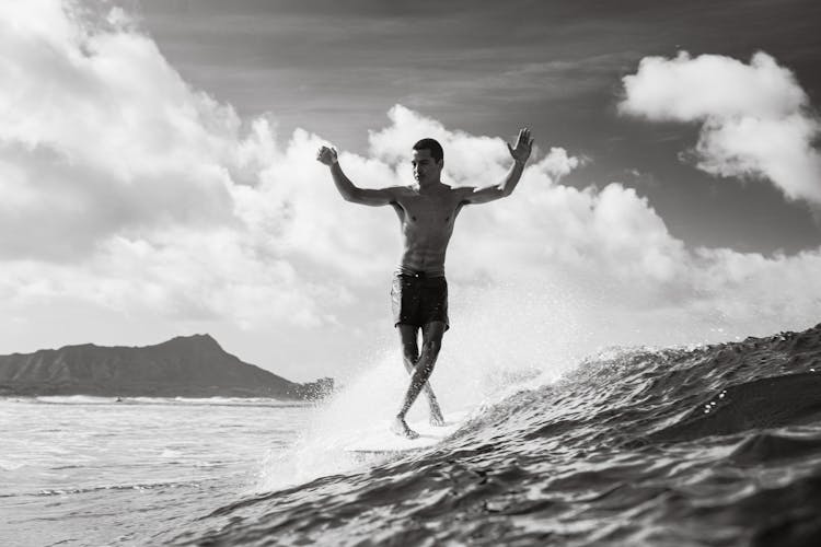 Black And White Shot Of Man Jumping Above Sea Water