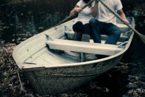 Man and Woman Sitting on Boat Holding Paddles