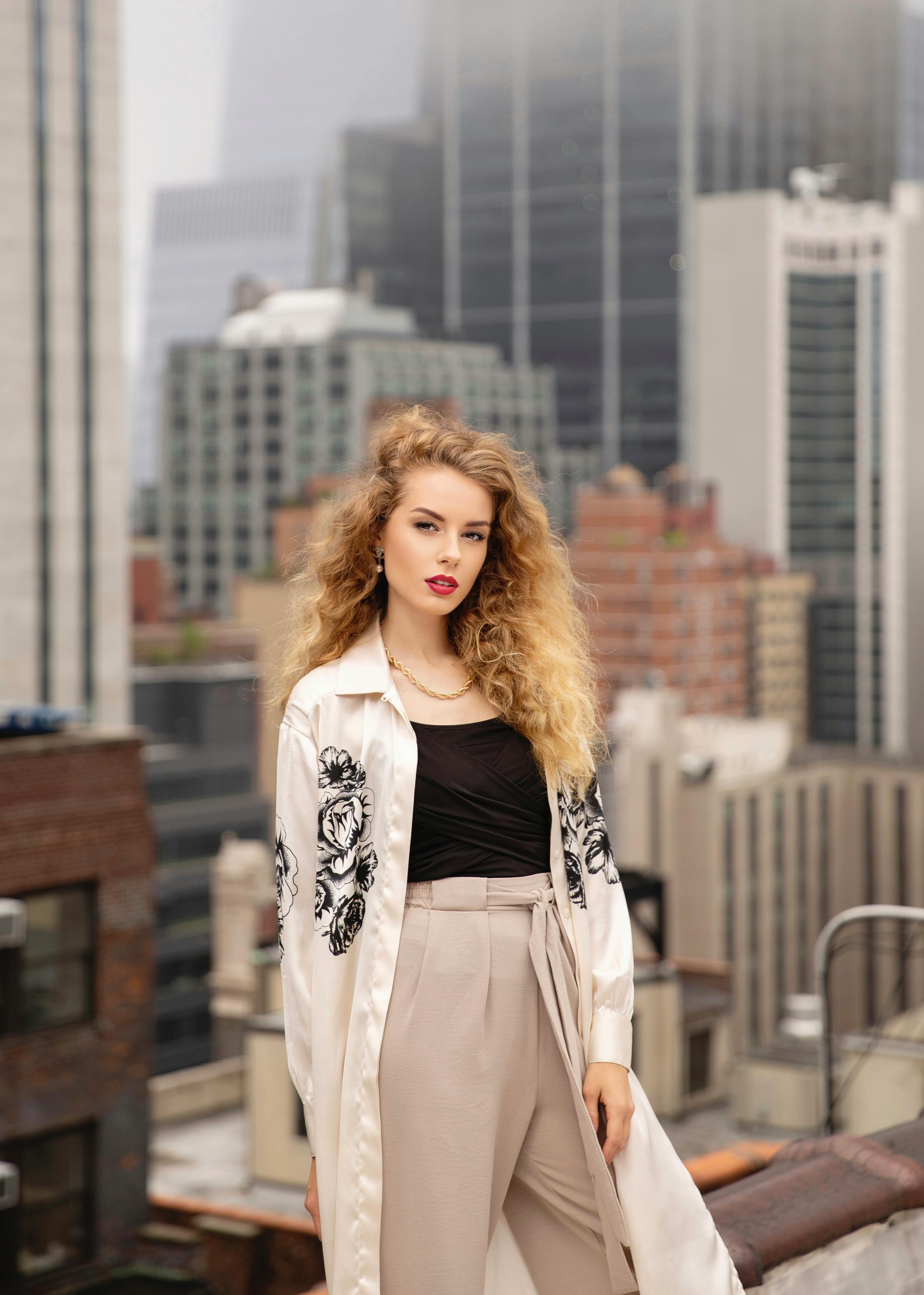 Stylish woman in a chic outfit posing on a New York City rooftop with skyscrapers in the background.