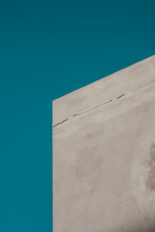 Free A stark minimalist concrete wall with cracks against a vivid blue sky in Abu Dhabi, UAE. Stock Photo