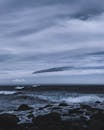 在戏剧性、喜怒无常的天空下，冰岛岩石海岸的迷人景色，海浪拍打着石头