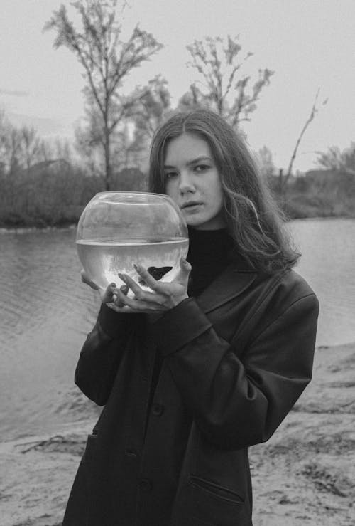 Woman in Black Coat Holding a Fish Bowl