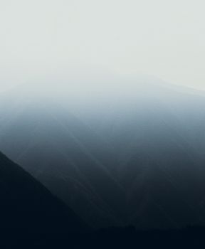 Serene mountain landscape shrouded in mist at dawn, creating a tranquil and ethereal scene.