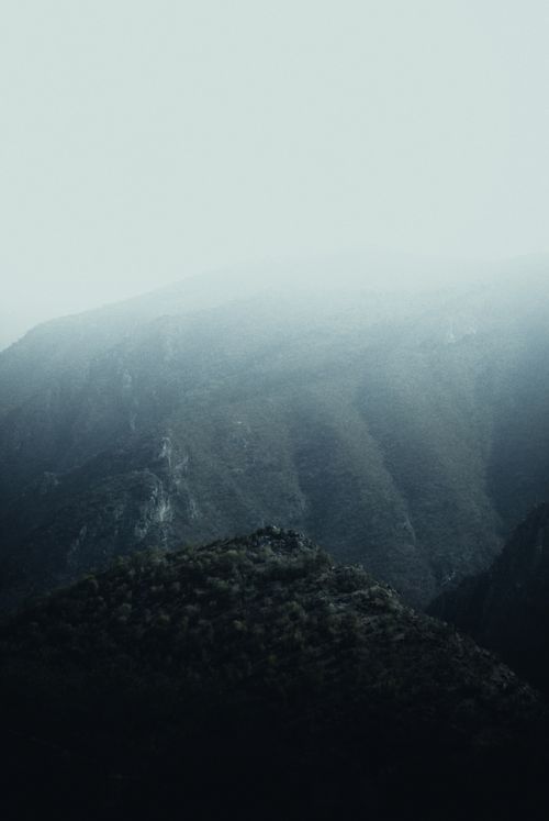 Free A foggy view of a serene mountain landscape with a valley and hills in the distance. Stock Photo