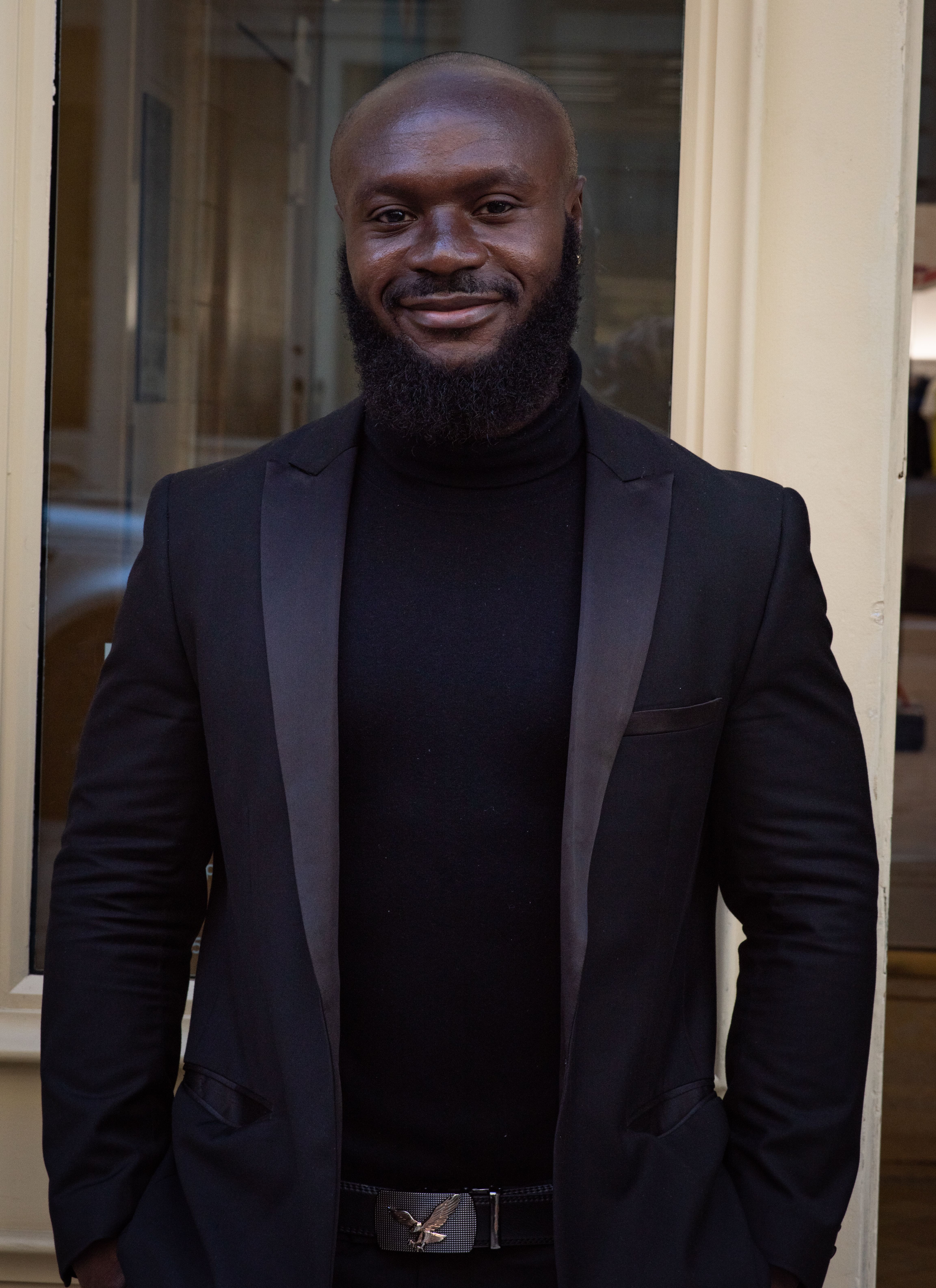 Portrait of a confident, smiling man in a formal black suit in New York City.