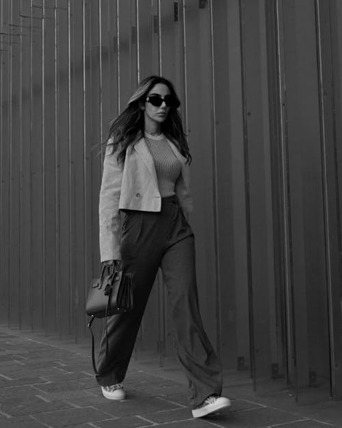 A Grayscale Photo of a Beautiful Woman Walking on the Street