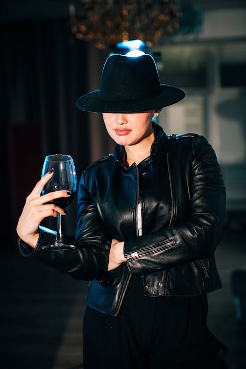 A Woman in Black Leather Jacket Holding Clear Drinking Glass