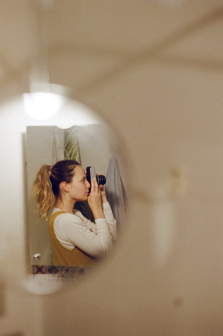 Woman Holding A Camera Reflecting In A Mirror 