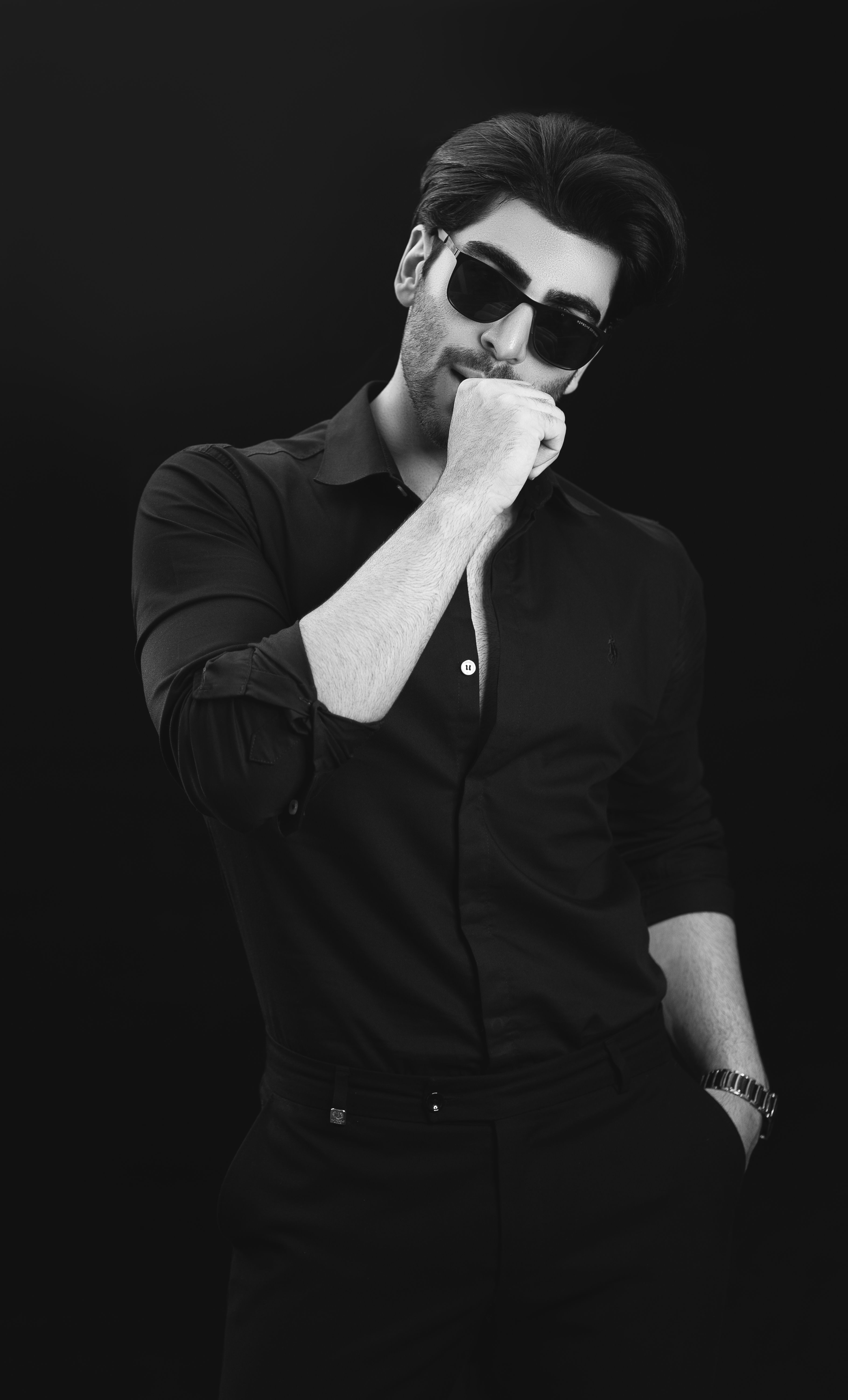 Black and white portrait of a stylish man posing confidently in sunglasses.