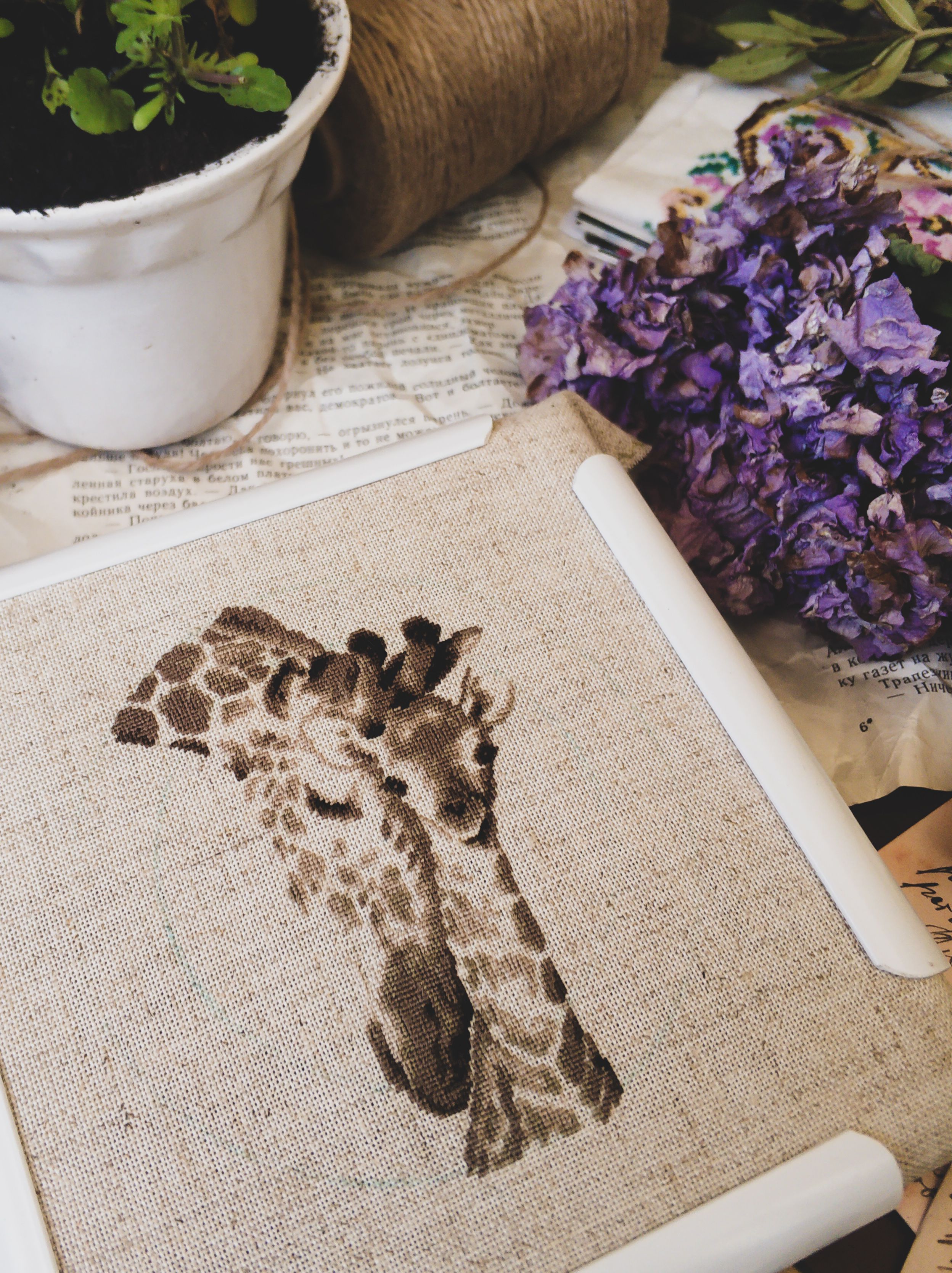 Detailed giraffe embroidery surrounded by flowers and plants, showcasing artistic craftsmanship.