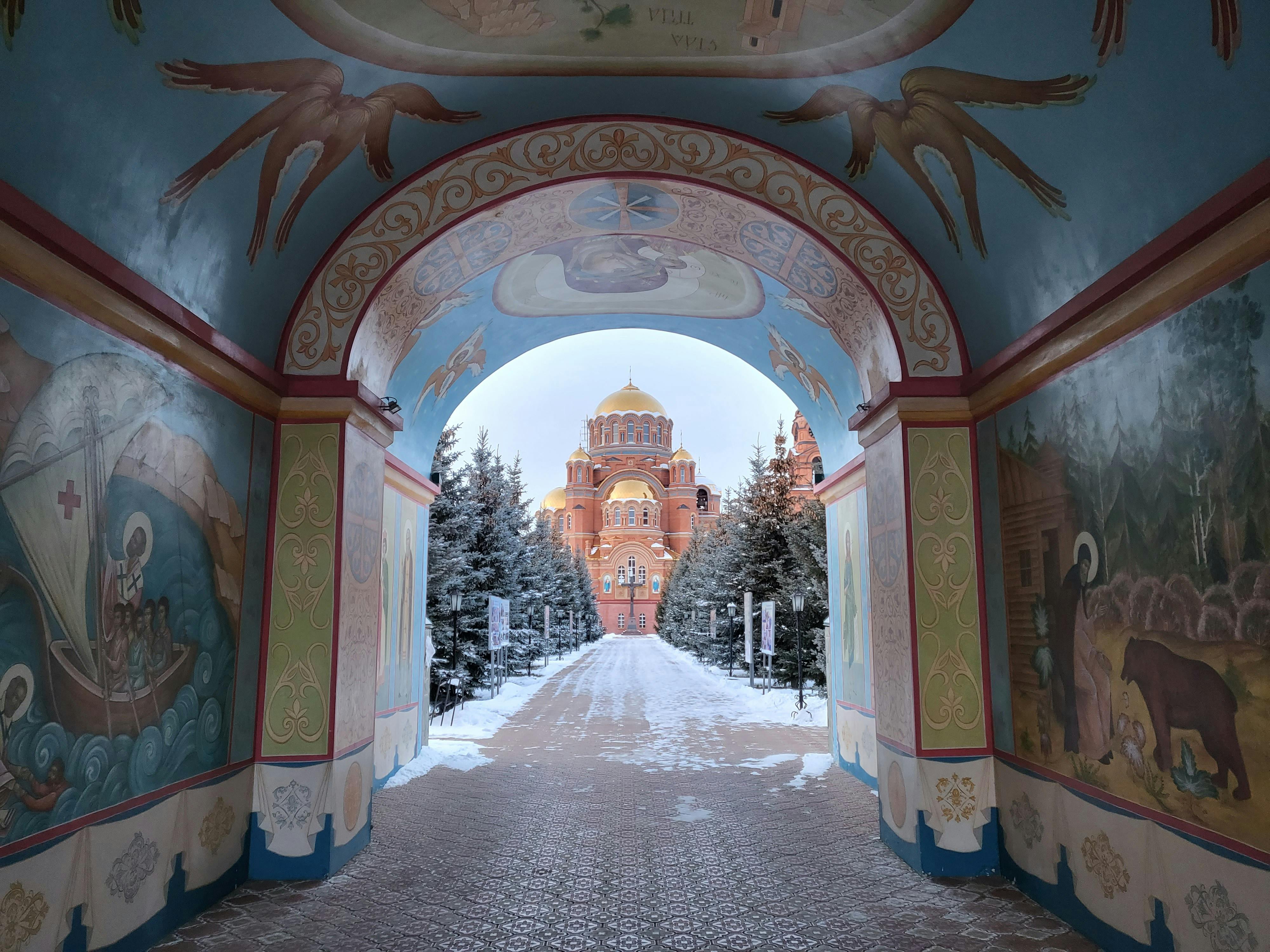 View through ornately decorated archway to a church in Saraktash, Russia, with winter scenery.
