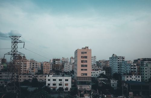 Free View of city buildings under cloudy skies, highlighted by prominent power lines. Stock Photo