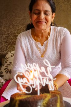 Woman smiling warmly as she enjoys a birthday celebration with cake.