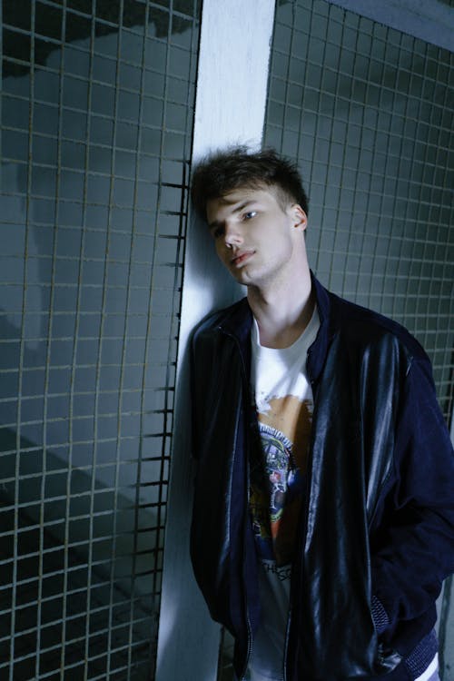 A Man in a Black Jacket Leaning His Head on a Metal Fence