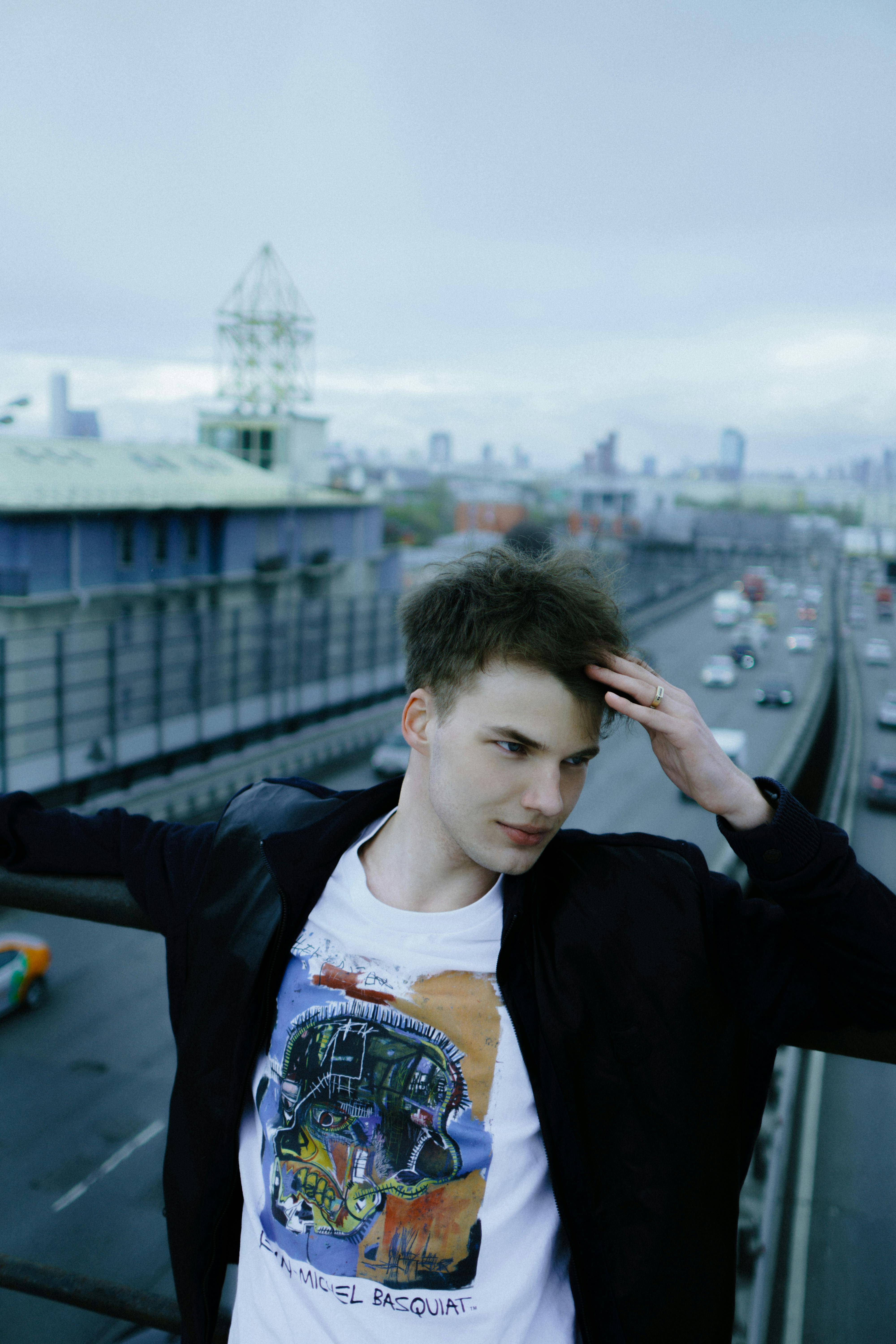 Young man in urban setting leaning on railing, day.