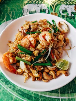 A vibrant close-up of authentic Thai seafood Pad Thai with shrimp, sprouts, lime, and cashews.