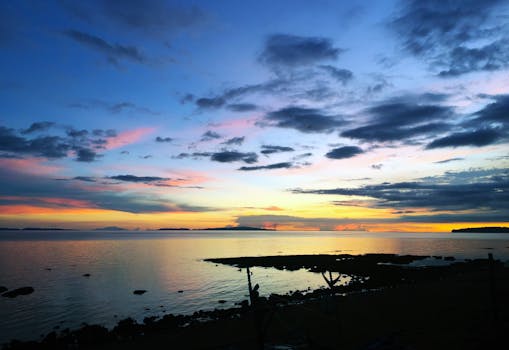 A breathtaking sunset over the serene coastline of Donsol, with vibrant colors reflecting on the water.