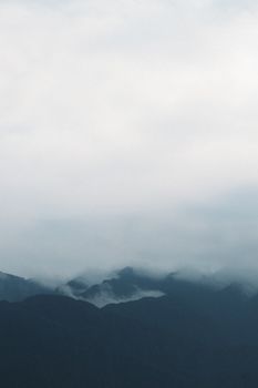 Misty mountain range shrouded in fog and clouds creating a serene landscape.