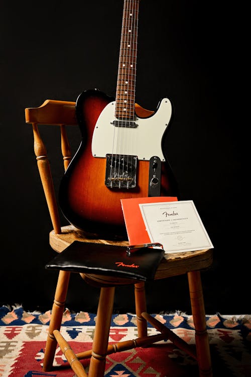 Free Brown and White Stratocaster Electric Guitar on Brown Wooden Chair Stock Photo