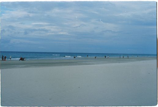 Serene beach scene in Da Nang, Vietnam with people enjoying the coastline under a cloudy sky.