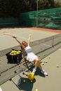 Woman in White Tank Top and White Skirt Sitting on Tennis Racket