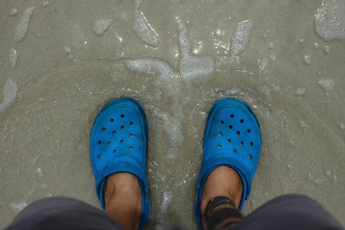Person Wearing Blue Rubber Clogs on the Beach