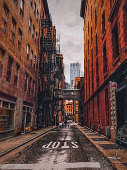 A city alley surrounded by tall buildings and a visible stop sign, perfect for urban exploration enthusiasts.