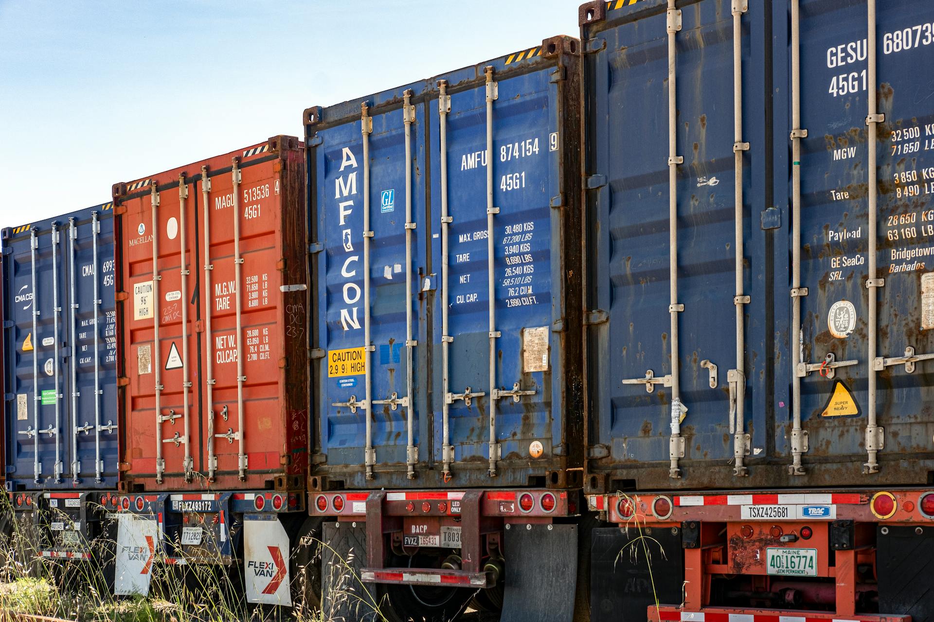 Row of colorful cargo containers in an industrial shipping yard, ready for transportation.