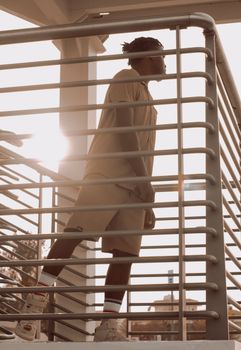 Profile of an adult man standing on a stairway, silhouetted against the sunset in Dubai.