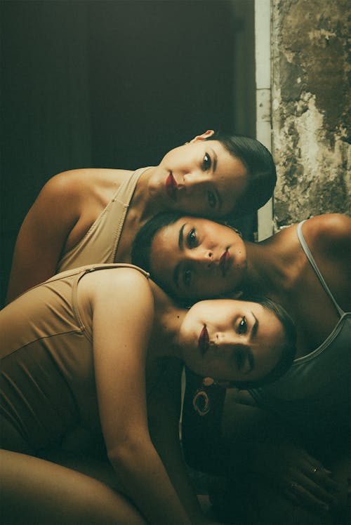 Free Three Brunette Women Posing for Artistic Portrait with Tilted Heads Stock Photo