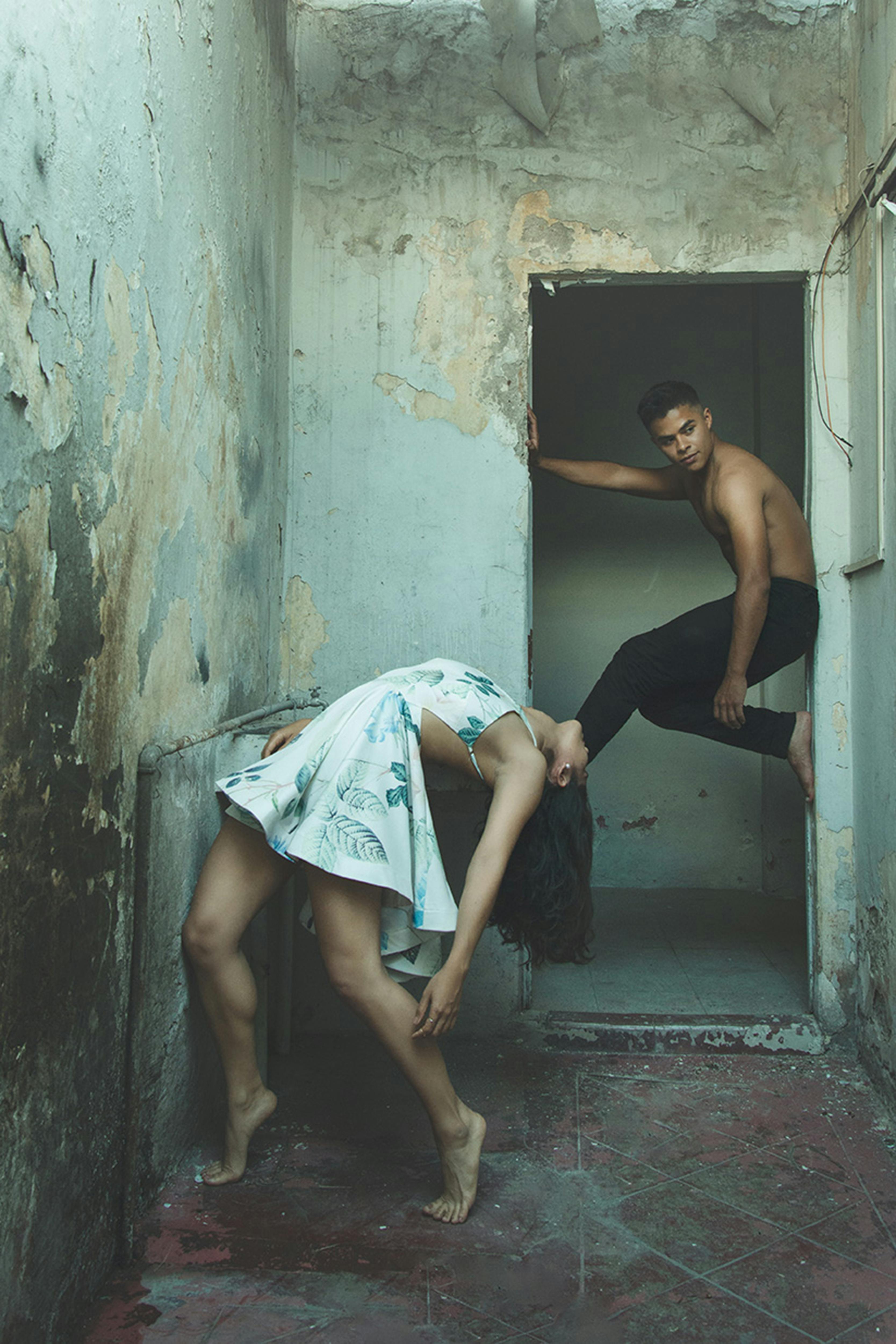 barefoot girl in dress tilting backwards and boy exercising in door