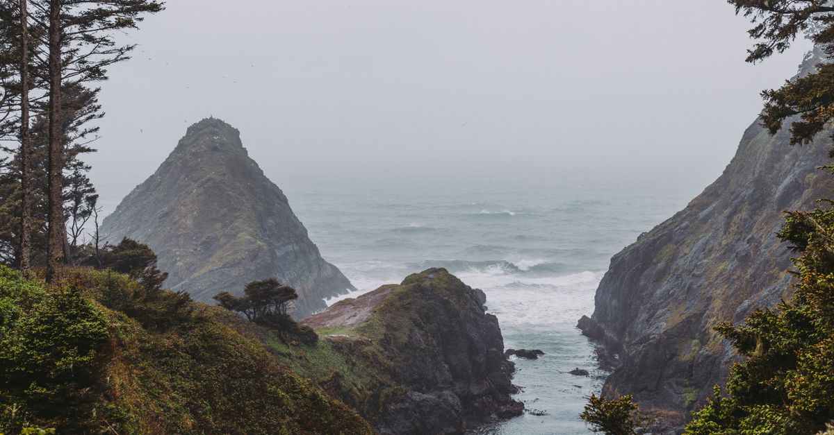 A stunning view of the rocky Oregon coastline showcasing cliffs, the sea, and greenery under a cloudy sky.