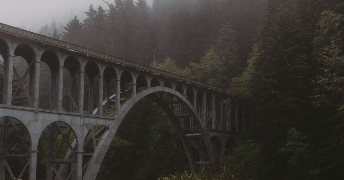 A captivating view of Cape Creek Bridge surrounded by misty forests in Florence, Oregon.