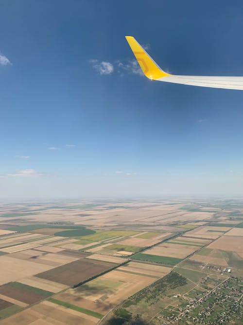 Wing of an Aircraft Flying over a Agricultural Land