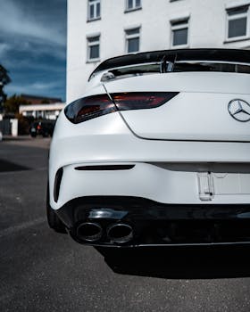 Close-up shot of a white luxury Mercedes coupe parked on a street, showcasing its sleek design.