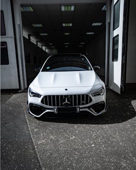 Front view of a sleek white Mercedes-Benz parked in a stylish garage entrance, showcasing luxury and elegance.