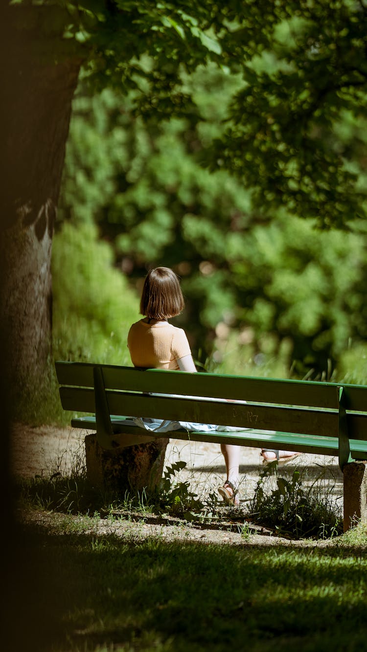 Girl In Summer Dress Sitting Alone On Bench In Park