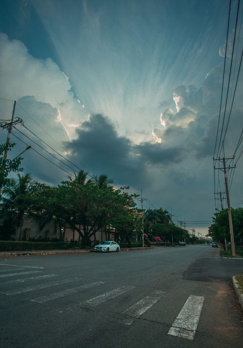 Free A dramatic sky with clouds over a quiet city street and pedestrian crossing. Stock Photo