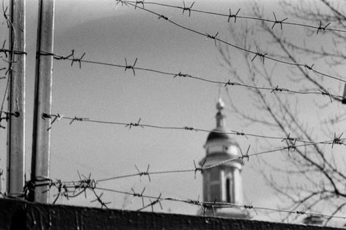 Free Black and white image of barbed wire with a Moscow church tower in the background. Stock Photo
