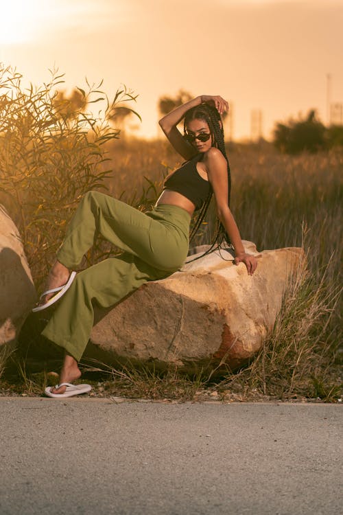 Woman in Black Crop Top Sitting on the Rock