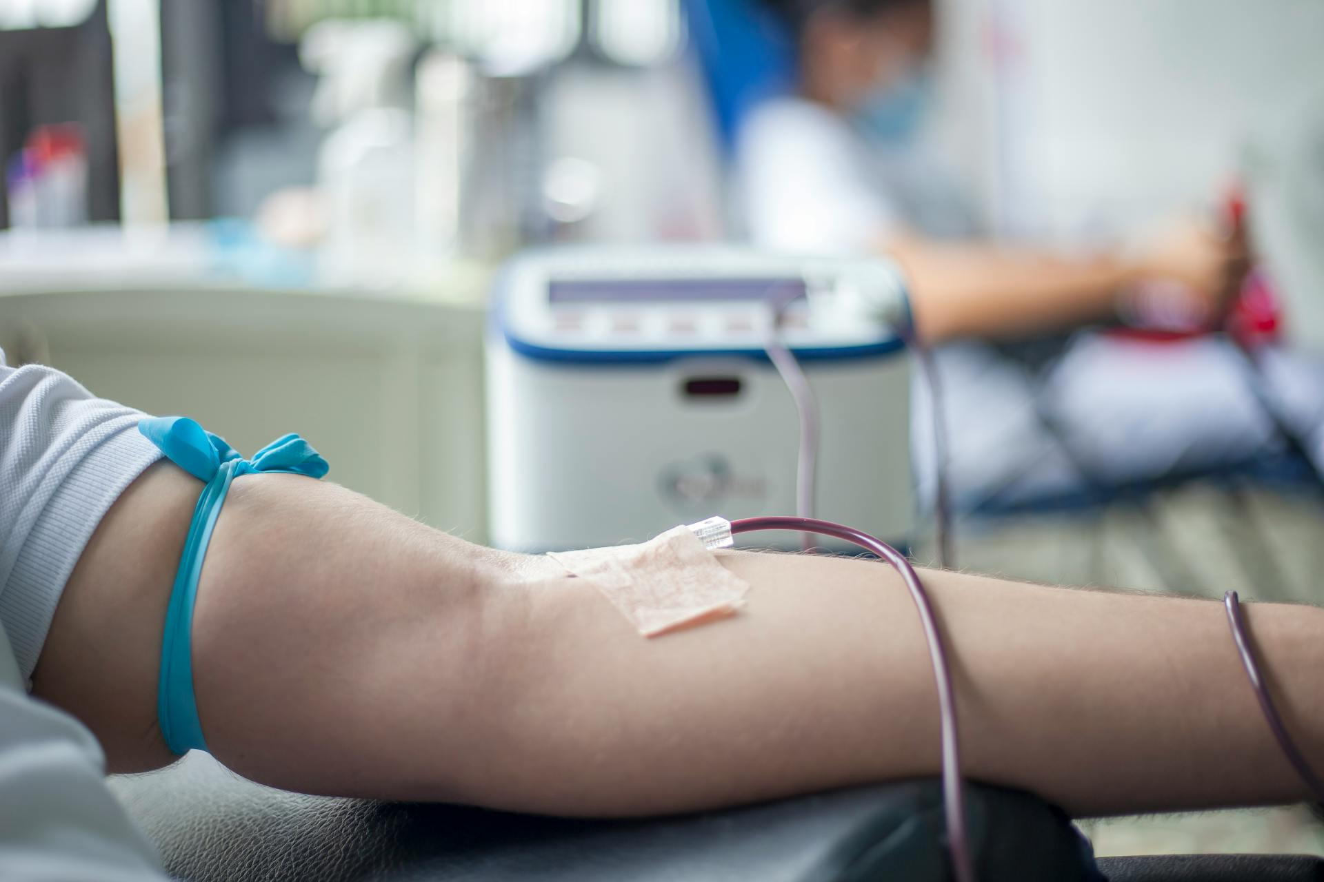 A detailed close-up of an arm during the blood donation process in a medical setting.