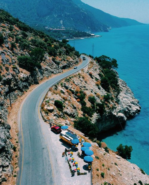 Free Aerial view of a winding road along a cliffside beside a turquoise ocean. Stock Photo