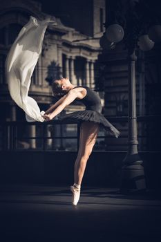 Captivating shot of a ballerina performing a graceful leap outdoors, draped in flowing fabric.