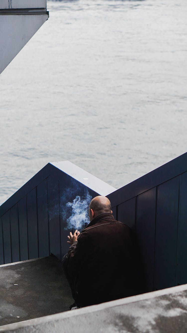 Man Sitting On Stairs Outside And Smoking A Cigarette