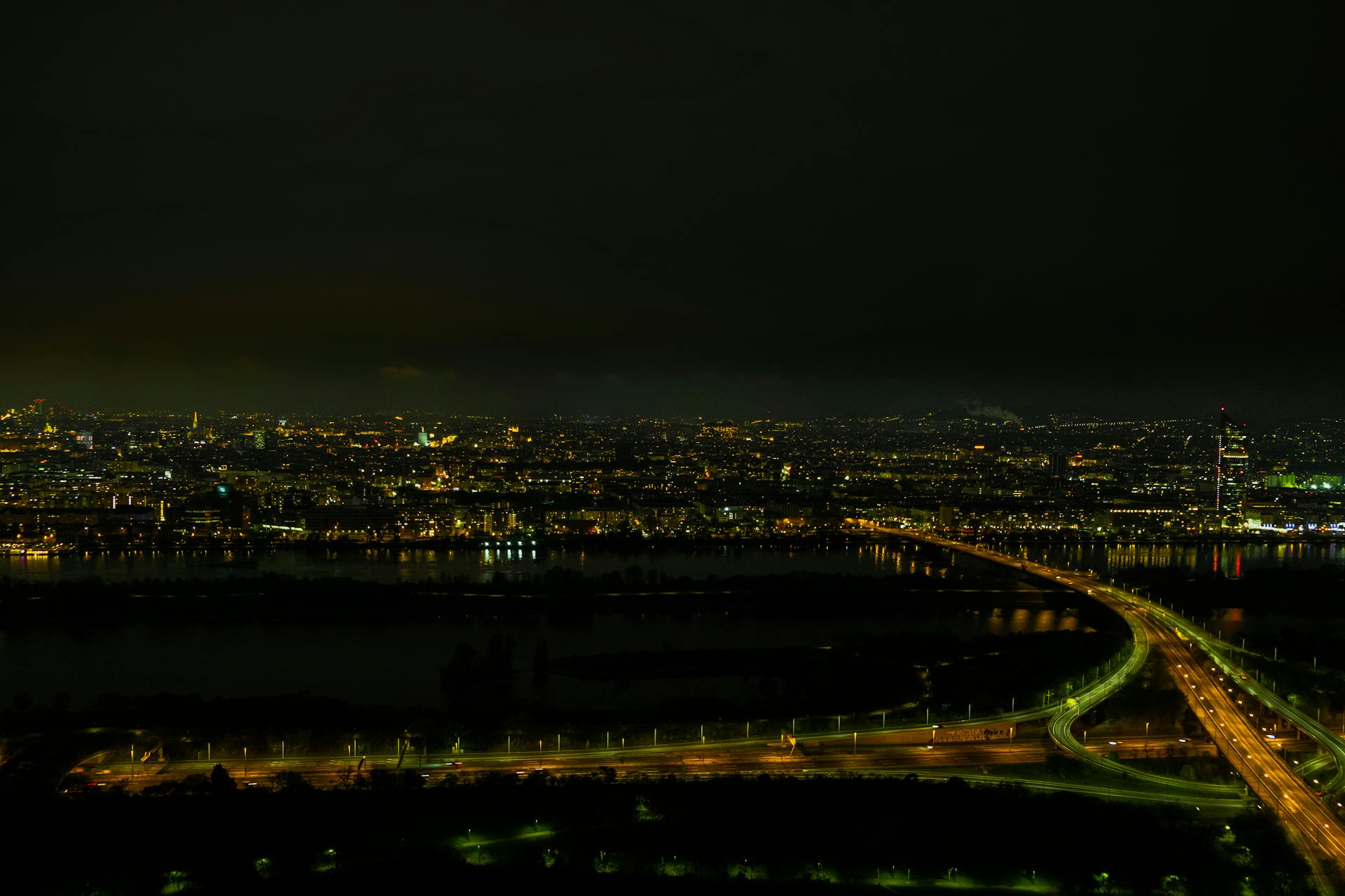 Experience the breathtaking nighttime aerial view of Vienna's cityscape with glowing city lights and dynamic urban layout.