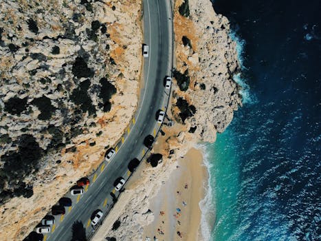 A stunning aerial shot of a coastline road alongside a pristine beach and azure sea.